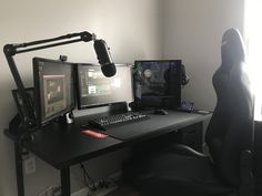 a computer desk with two monitors and a microphone