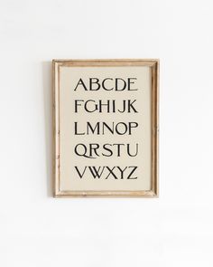 a wooden frame hanging on the wall with an alphabet written in black and white letters