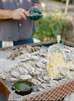 a man standing next to a table filled with oysters