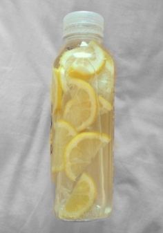 a bottle filled with lemon slices sitting on top of a white sheet