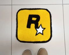 someone is standing on the floor next to a rug with a letter r and star