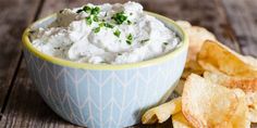 a bowl filled with white dip surrounded by chips