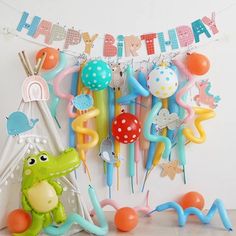 a birthday decoration with balloons and toys hanging from the wall next to a teepee tent