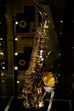 a saxophone sitting on top of a glass table in front of a sound equipment display case