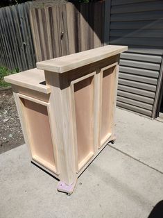 a wooden cabinet sitting on top of a cement floor next to a fence and building materials