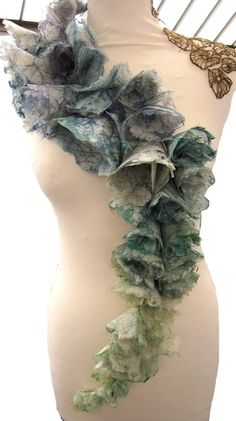 a white mannequin with green and blue ruffles on it's neck