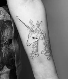 a black and white photo of a unicorn tattoo on the arm