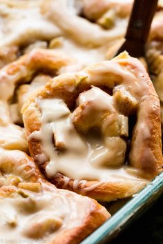 a pan filled with cinnamon rolls covered in icing