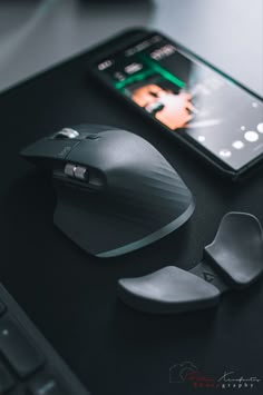 a computer mouse, cell phone and other items on a black desk with the image of a woman's face