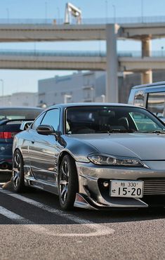 a silver sports car parked in a parking lot next to other cars on the street