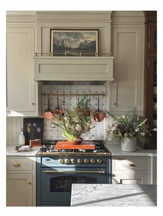 a stove top oven sitting inside of a kitchen next to a painting on the wall