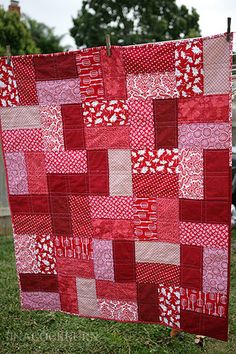 a red and white quilt hanging from a clothes line