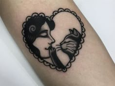 a woman's face in a heart shaped frame tattoo on the left arm and shoulder