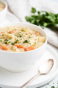 two bowls of soup on a plate with spoons and parsley in the background