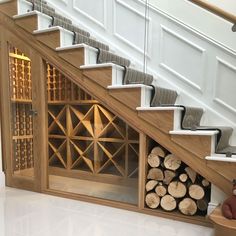 there is a wine rack under the stairs next to some firewood stacked on top of each other