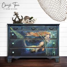 an old dresser painted with mermaids on it