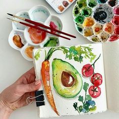 someone is painting an avocado with watercolors and other paints on the table