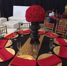 a black table topped with red and gold place settings