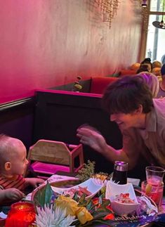 a man and child sitting at a table in a restaurant with food on the table