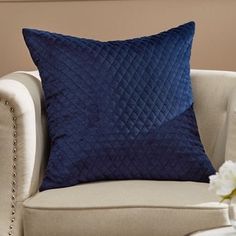 a blue pillow sitting on top of a white chair next to a vase with flowers