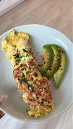 an omelet is on a white plate with avocado