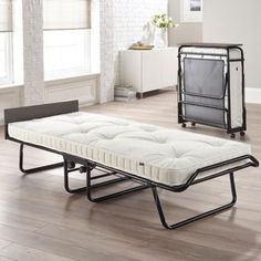 a white bed sitting on top of a wooden floor next to a black metal frame