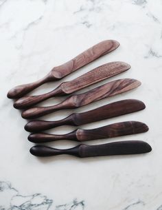 five wooden spoons lined up on a marble surface