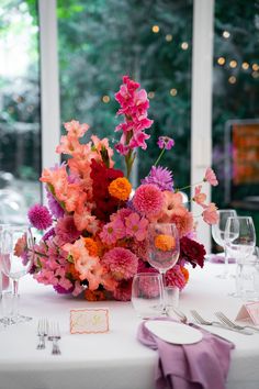 the table is set with pink and orange flowers