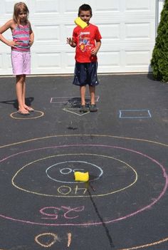 two young children standing in front of a chalk drawing on the ground with numbers and arrows