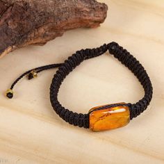 Circling the wrist with hand-knotted macrame cord in black this unisex bracelet from Mexico is designed by artisan duo Jacqueline and Eddy. This impressive accessory is centered by a pendant of amber gleaming with ancient beauty. A sliding knot gives this bracelet an adjustable length. Petite amber accents dangle from the clasp. Black Jewelry With Adjustable Cord For Healing, Adjustable Silk Cord Jewelry With Sliding Knot, Hand Wrapped Black Jewelry With Waxed Cord, Handmade Black Jewelry With Nylon Cord, Handmade Black Nylon Cord Jewelry, Handmade Black Nylon Cord Bracelets, Macrame Bracelet Jewelry In Nylon Cord, Macrame Nylon Cord Bracelet Jewelry, Black Bohemian Bracelet With Waxed Cord