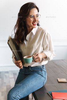 a woman sitting at a table with a cup of coffee and folders in her hands - stock photo - images