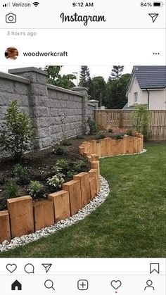 a garden with wooden planters and rocks in the grass next to a brick wall