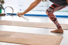 a woman standing on top of a yoga mat with her leg in the air while holding a bottle