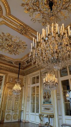 an ornate chandelier hangs from the ceiling in a room with gold trimmings