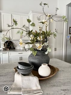 a vase with flowers in it sitting on a table next to two bowls and towels