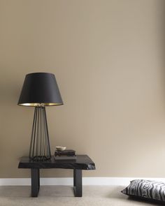 a lamp sitting on top of a wooden table next to a pillow in a room