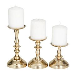 three brass candlesticks with white candles in them, on a white background photo