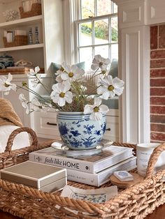 a wicker basket with books and flowers in it on top of a coffee table