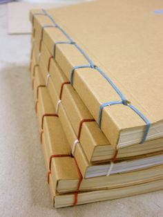 several books stacked on top of each other with blue string wrapped around the edges,