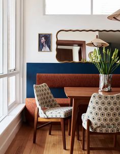 a dining room table with two chairs and a vase filled with flowers