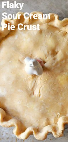 a pie crust in a pan with a piece of cream on top and the words flaky sour cream pie crust above it