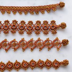 three different types of beaded bracelets on a white surface, one is orange and the other has gold beads