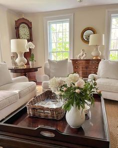 a living room filled with white furniture and lots of flowers on top of a coffee table