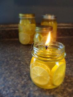 three mason jars filled with lemons and one has a lit candle in the middle