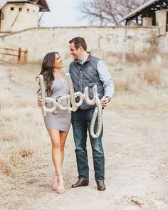 a man and woman holding up the word goodbye in front of their faces while standing on a dirt road