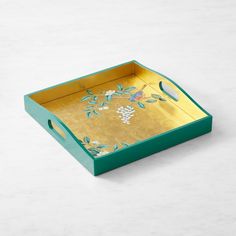 a green and gold serving tray with grapes on the vine painted on it, sitting on a white surface