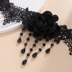 Introducing the Gothic Black Lace Jewelry Set, a stunning combination of elegance and dark allure. This set features a beautifully detailed lace choker adorned with a dark rose centerpiece, complemented by matching earrings and a bracelet. The centerpiece of the necklace showcases a water drop crystal tassel, adding a touch of drama and sophistication. Perfect for adding a gothic touch to your Halloween look, cosplay, or any special occasion, this jewelry set is crafted for women who embrace bol Black Lace Party Jewelry, Adjustable Lace Jewelry For Parties, Elegant Adjustable Halloween Jewelry, Black Rose Design Party Jewelry, Elegant Black Jewelry With Rose Design, Elegant Rose Design Choker, Crystal Tassel Necklace, Black Rose Flower, Rose Choker