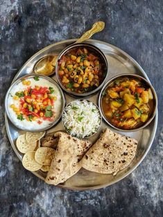 a silver plate topped with different types of food on top of a metal tray next to tortilla chips