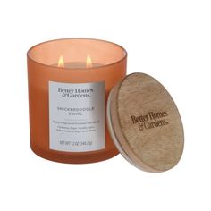 an orange candle sitting next to a wooden container with the label better homes and gardens on it