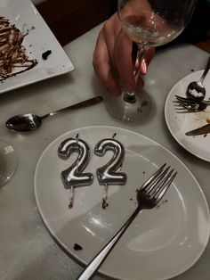 a person holding a fork and knife in front of a plate with the number 22 on it